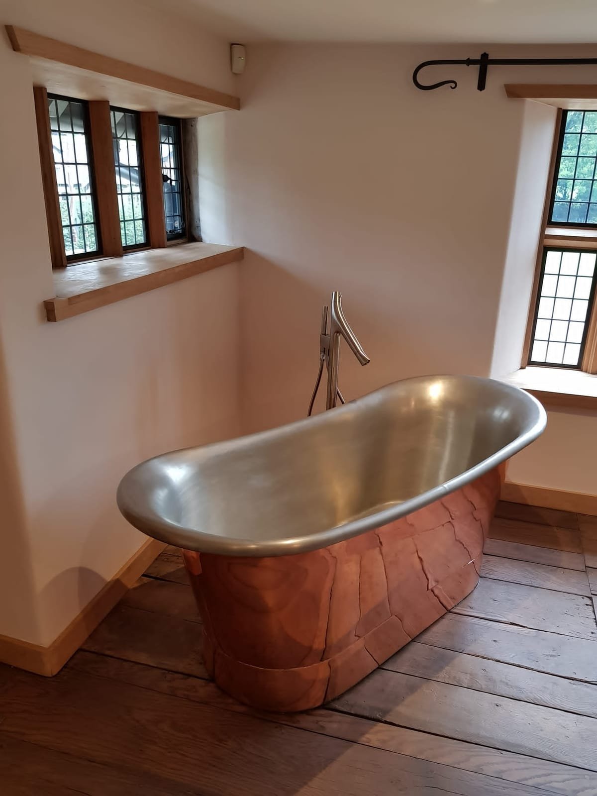 Copper bateau bath beneath exposed oak roof beams