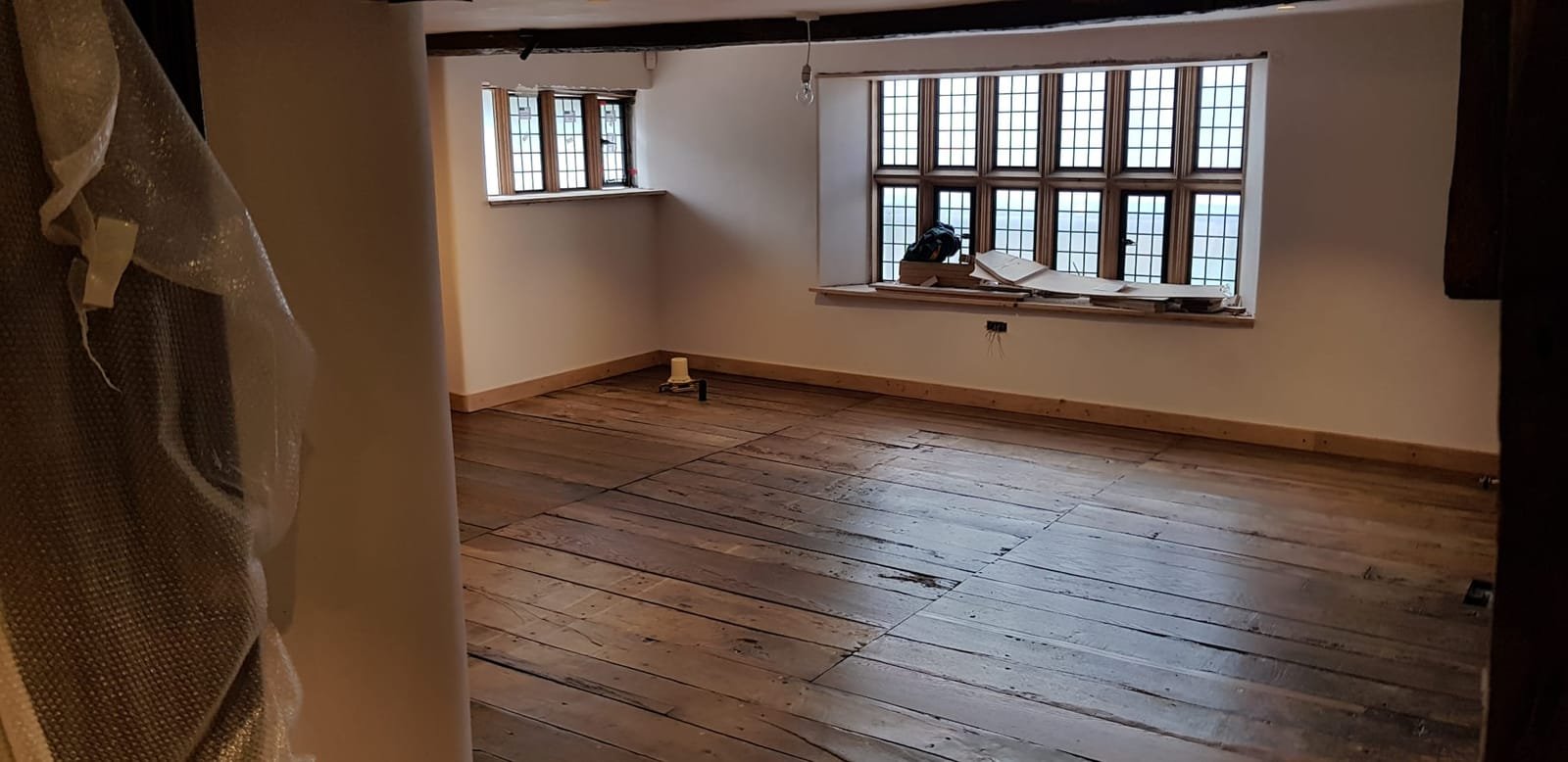 Reclaimed wide oak floorboards and leaded windows in oak reveals