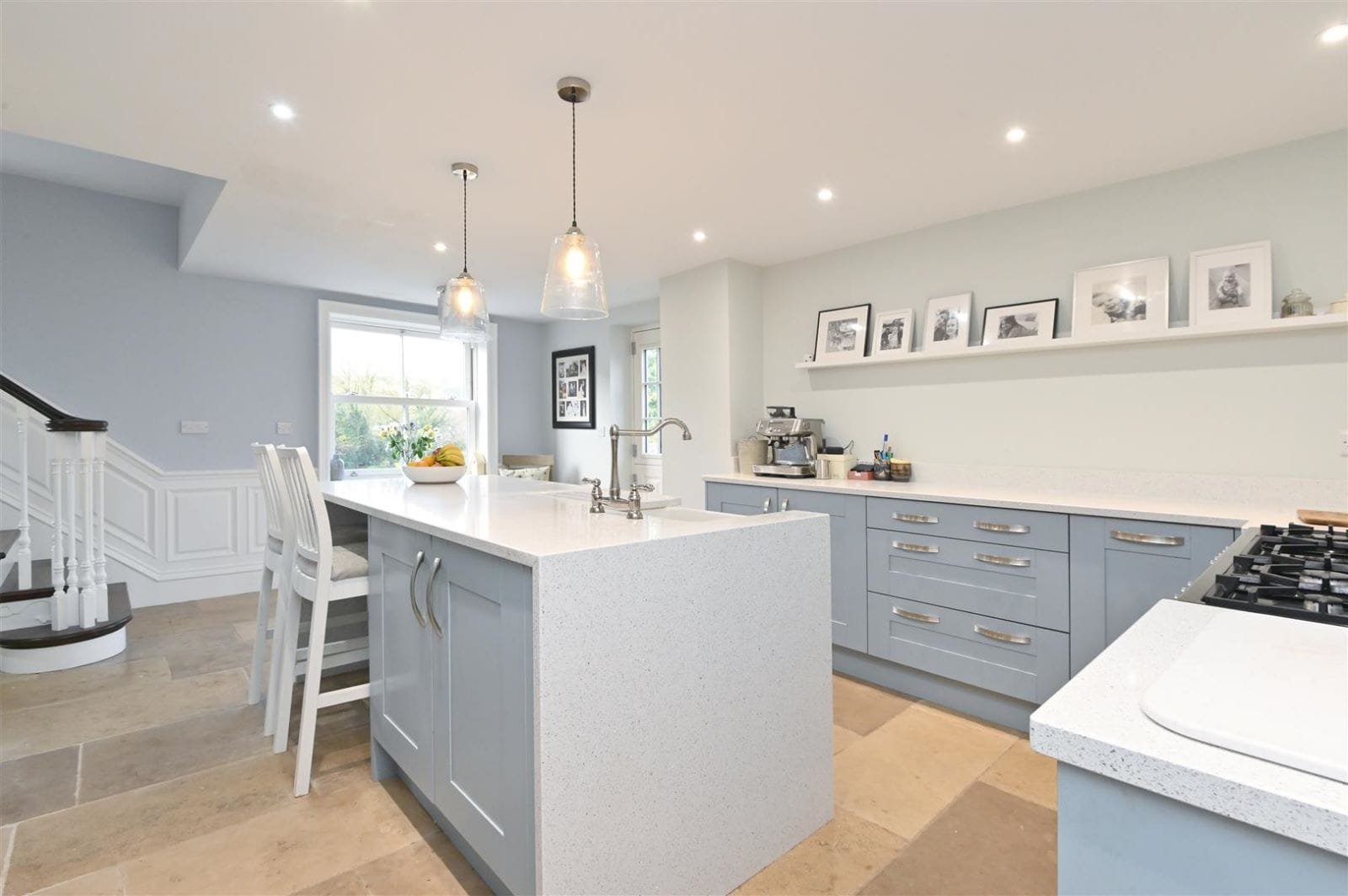 Duck-egg blue shaker kitchen with quartz worktops and limestone floor